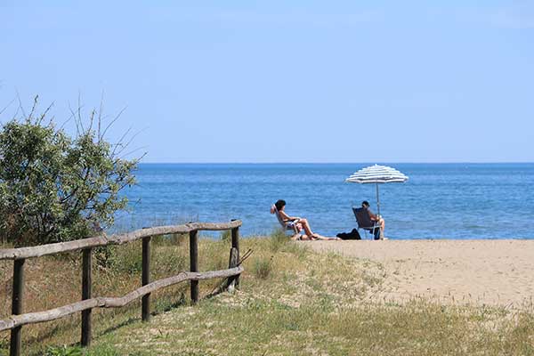 Beach and sea with pedalo and boys lying down to sunbathe